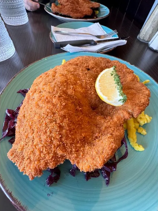 Wiener schnitzel with a lemon wedge on red cabbage and spätzle